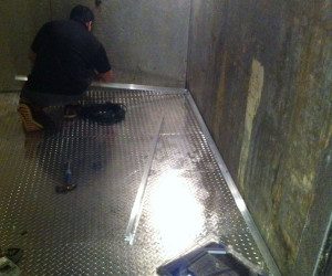 A man working on the floor of a bathroom.